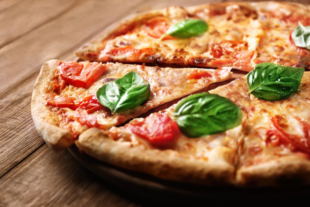 Delicious pizza with tomatoes and fresh basil on wooden background